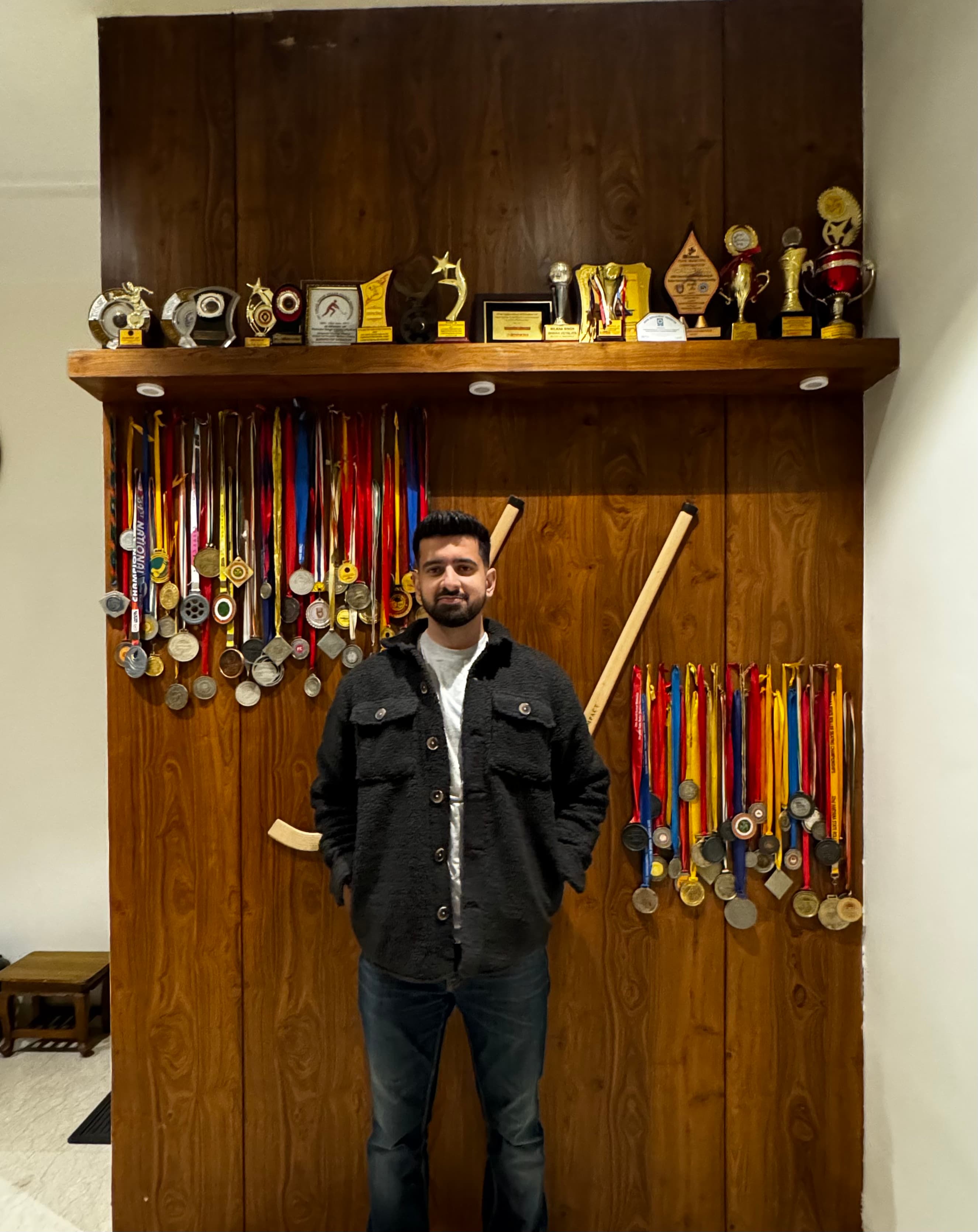 Parth in front of his medal wall at home